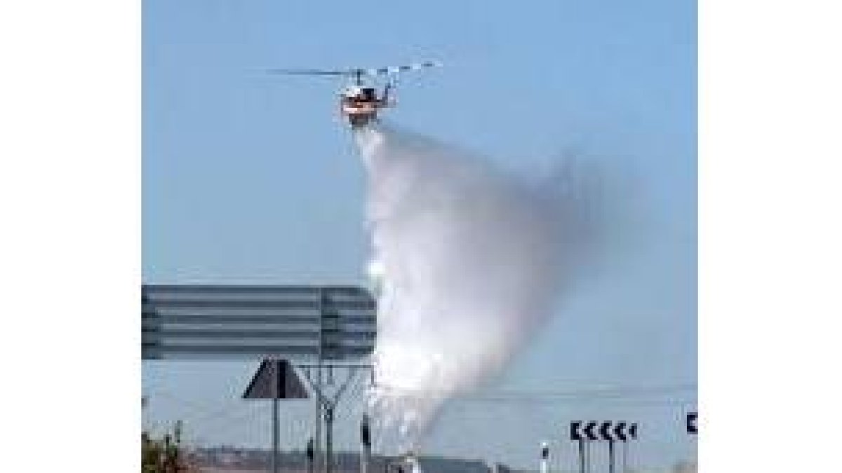 Un helicóptero arroja agua sobre el incendio, cerca de León