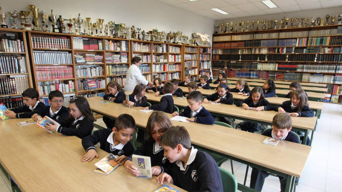 Varios niños ojean libros en una de las aulas del colegio La Asunción, que acoge a cerca de 700 alumnos que cursan desde Infantil hasta segundo de Bachillerato en el centro educativo leonés.