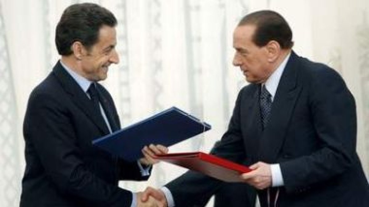 Berlusconi y el Sarkozy intercambian documentos después de firmar un acuerdo sobre energía atómica