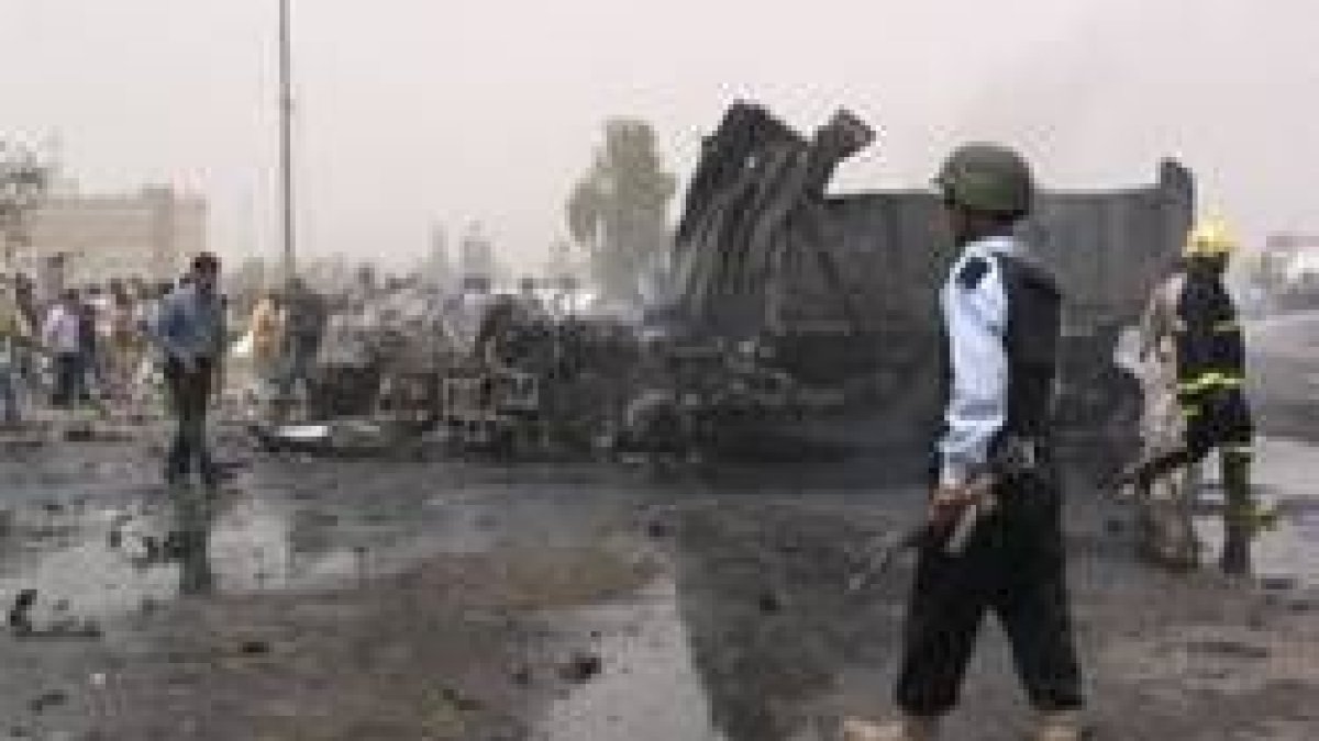 Un iraquí pasa junto a uno de los vehículos que las explosiones incendiaron en Kirkuk