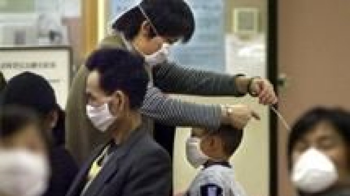 Una mujer coloca a su hijo una mascarilla en el servicio de urgencias de un hospital de Hong Kong