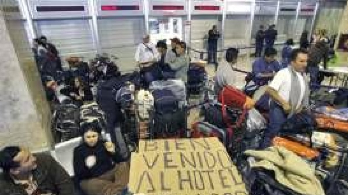Unos pasajeros de Air Madrid esperan junto a su equipaje en Barajas