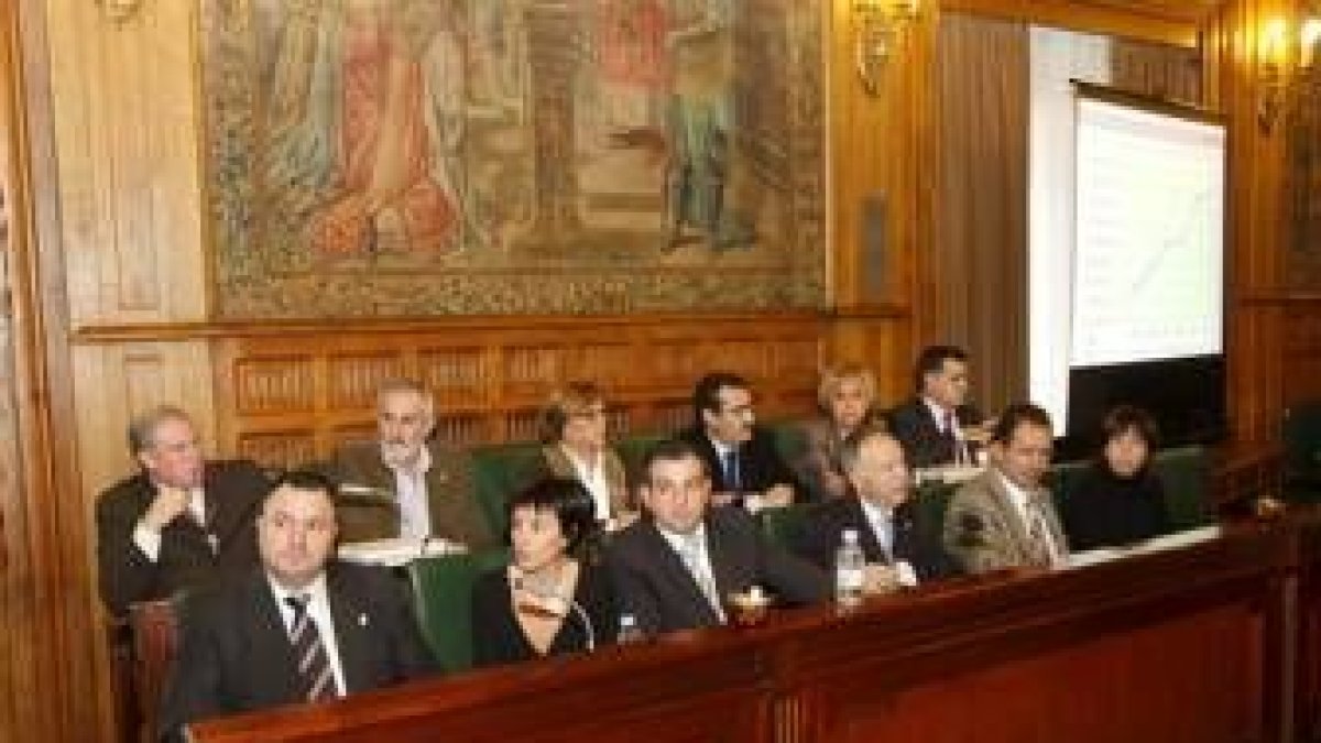 La oposición sigue el debate en un momento del Pleno, al fondo uno de los paneles Power Point