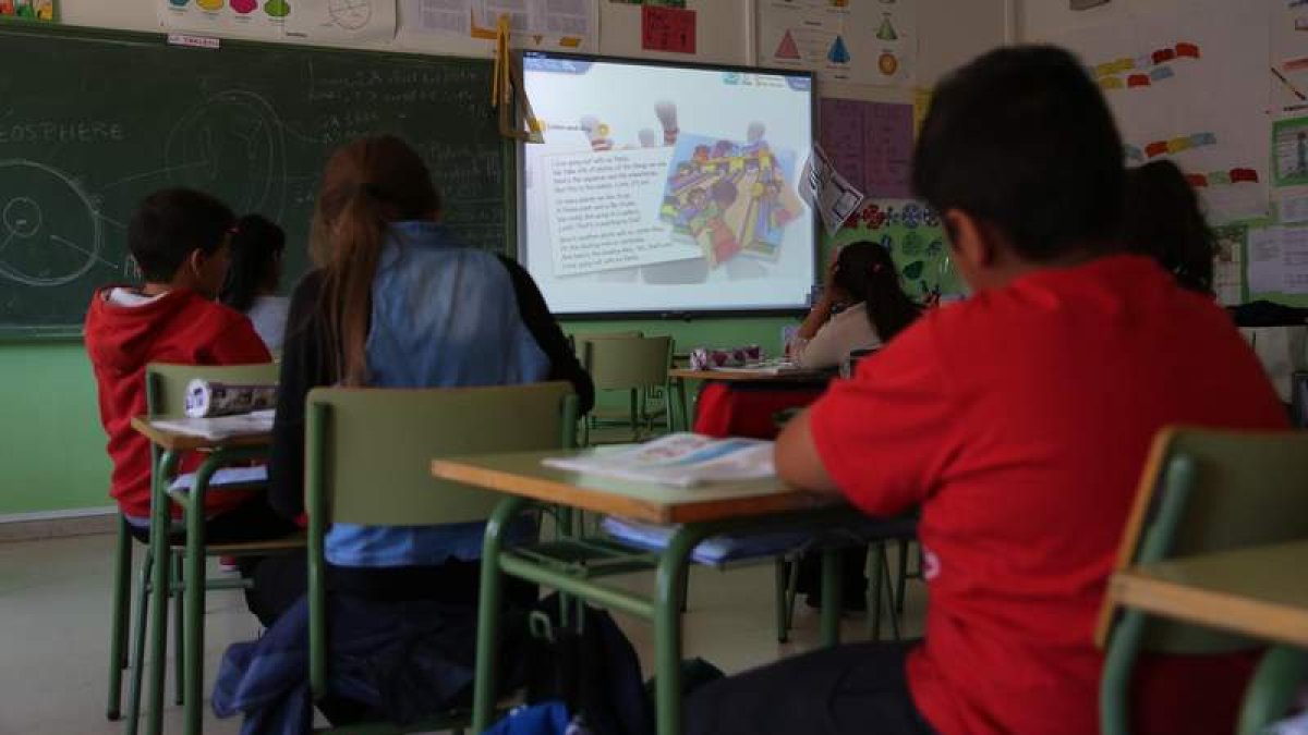 Un grupo de niños atiende las explicaciones de la plantalla electrónica en un colegio de León