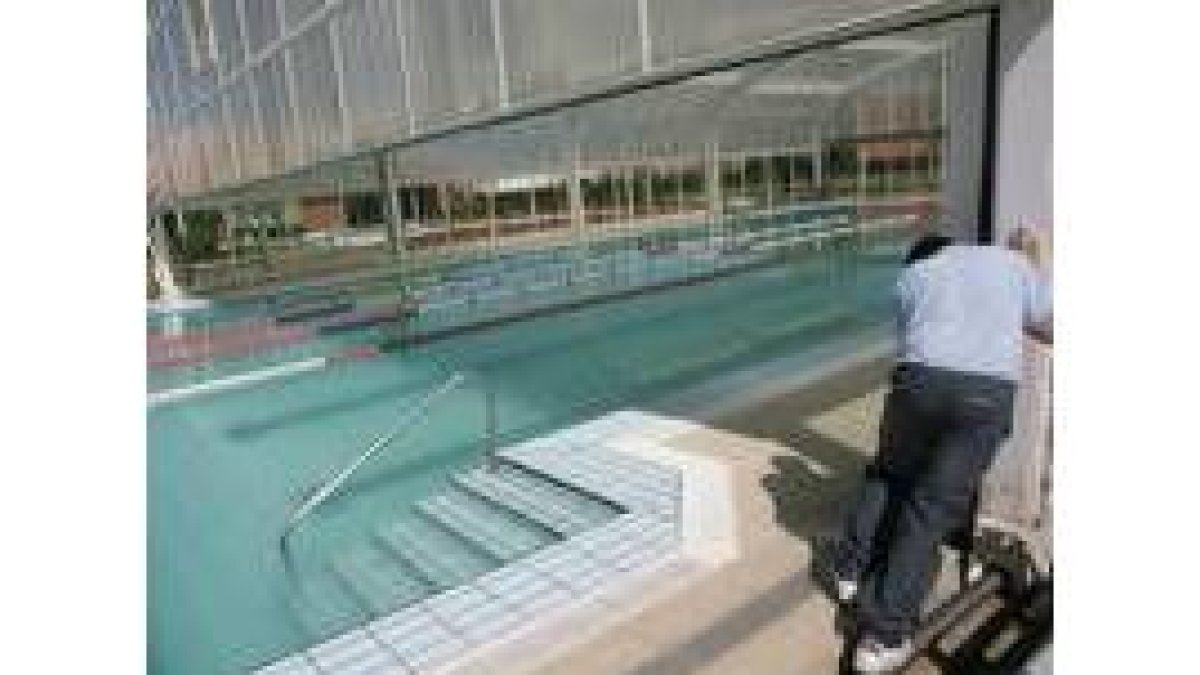 Un operario retira la cubierta de la piscina de Trobajo