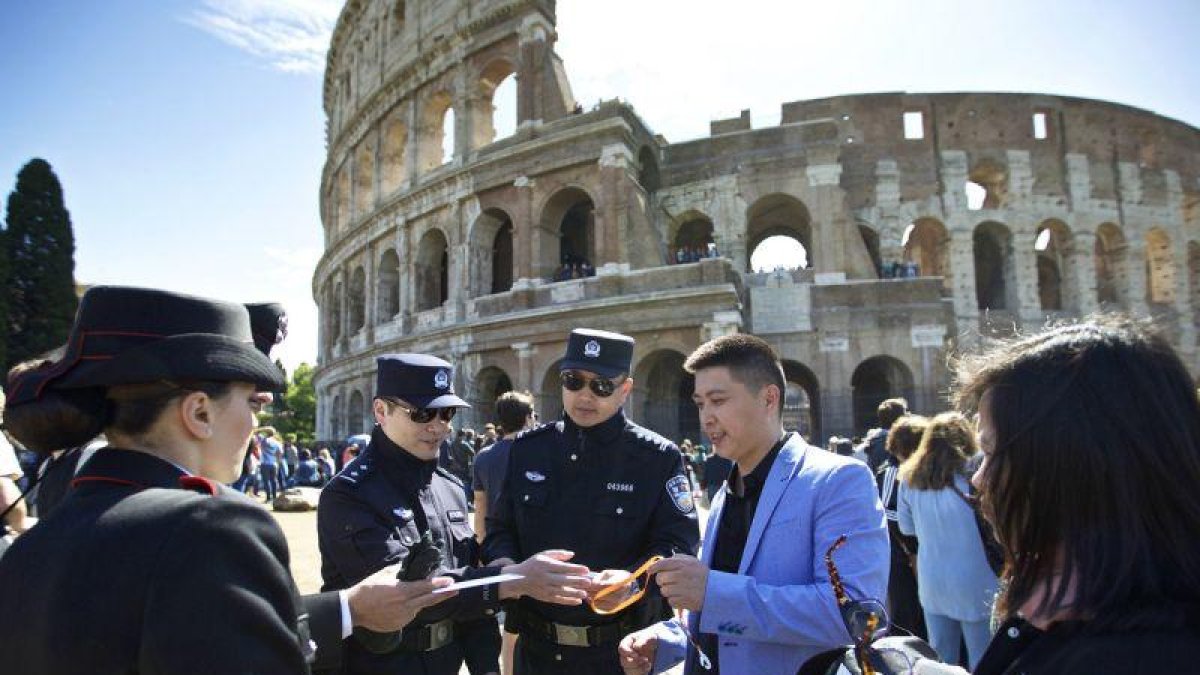 Dos agentes chinos, junto a dos italianos, revisan la documentación de un grupo de turistas chinos, en el exterior del Coliseo, en Roma, este lunes.