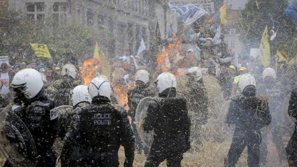 Los ganaderos participantes en la manifestación lanzan paja contra los antidisturbios, ayer, en Bruselas.