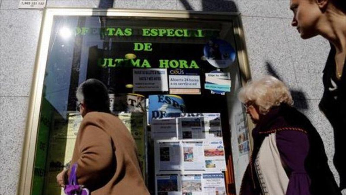 Varias personas miran el escaparate de una agencia de viajes, en Madrid.