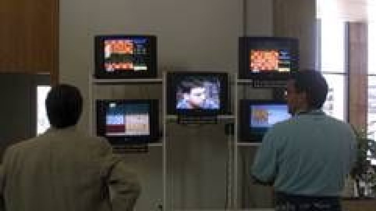 Dos consumidores observan unos televisores en una tienda de León