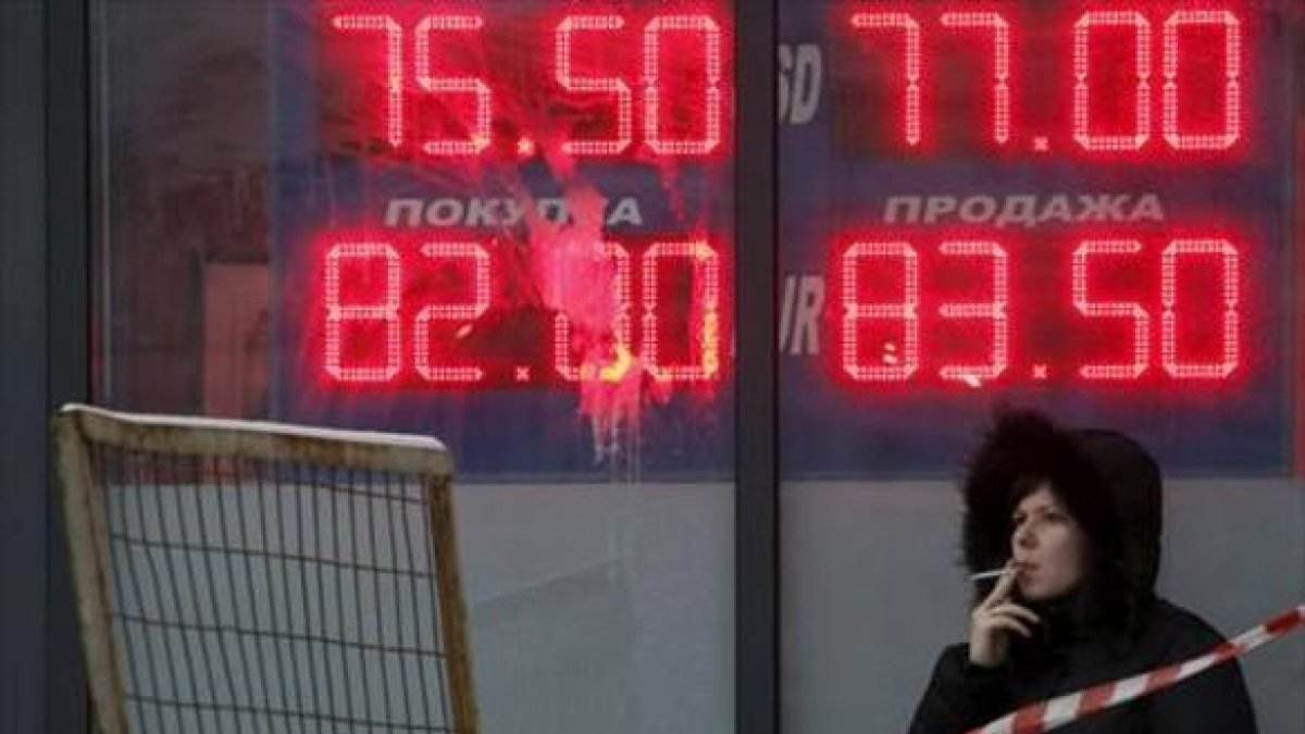 Una mujer, ante un panel que muestra el cambio del rublo ante el euro y el dólar, en Moscú.