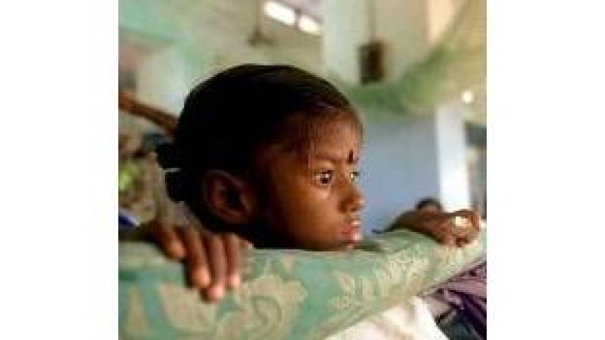 Una niña seropositiva permance en una cama de un hospital de la India