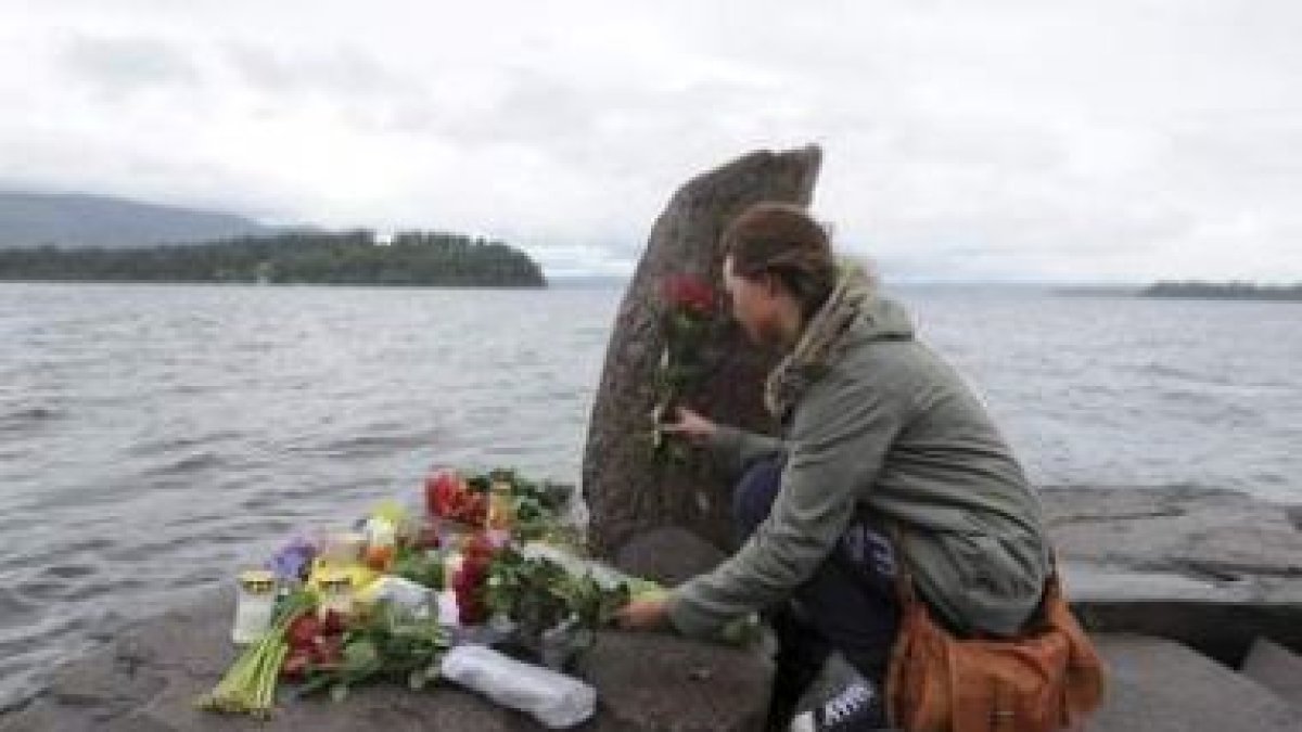 Una joven deja flores ante un monumento improvisado.