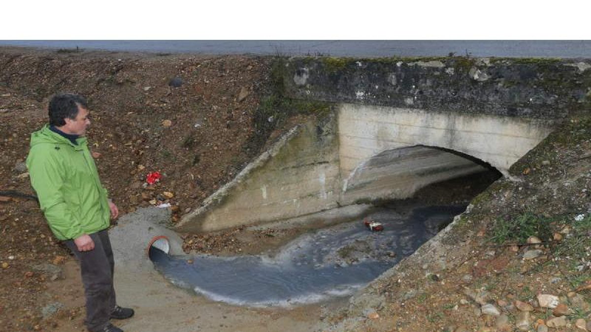 El edil del Mass en el Ayuntamiento de Cubillos observa el vertido azulado que enturbió ayer las aguas del arroyo de la Dehesa.