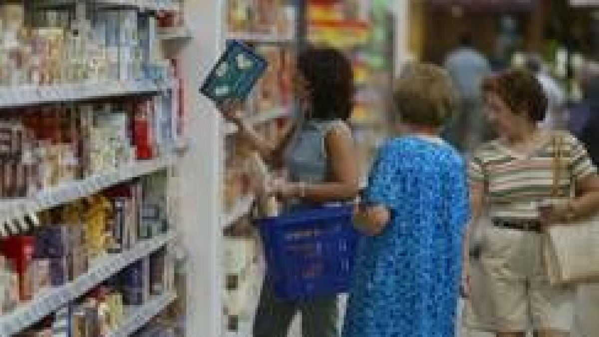 Tres mujeres contemplan los productos y los precios en un supermercado de León