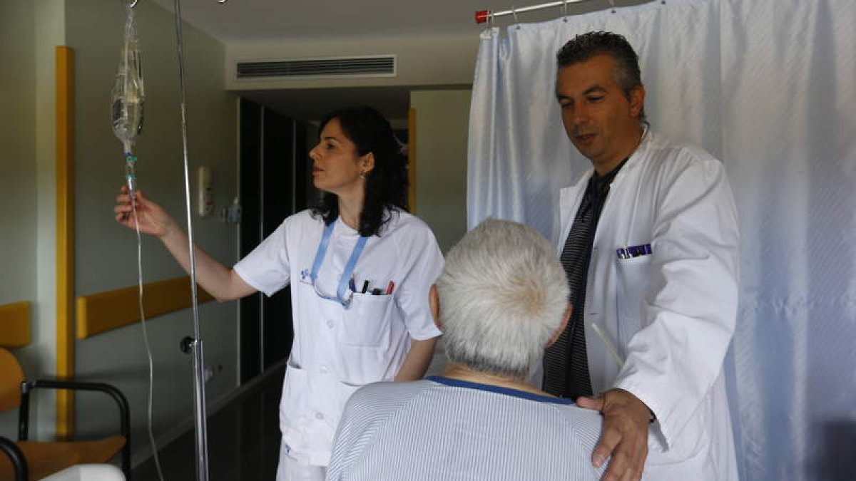 Ana Rosa Álvarez, enfermera, y Alberto Morán, internista, atienden a un enfermo en la unidad en el Hospital de León.