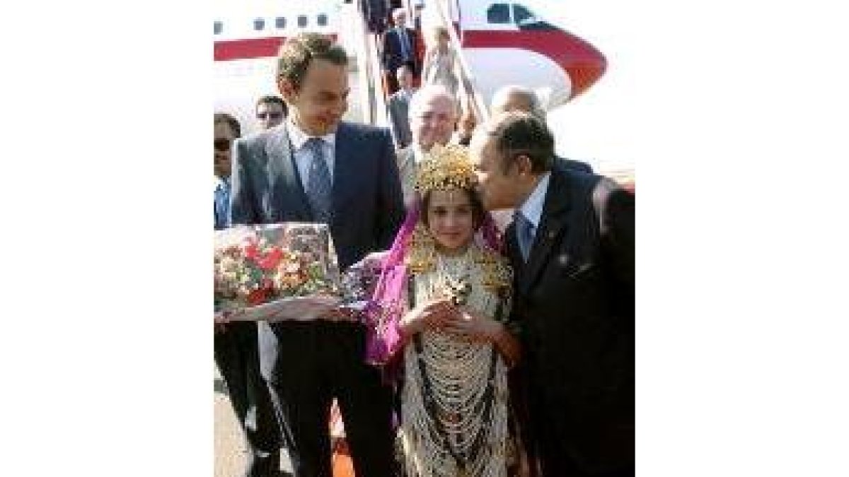 Una niña con el traje argelino recibe a Zapatero con un ramo de flores