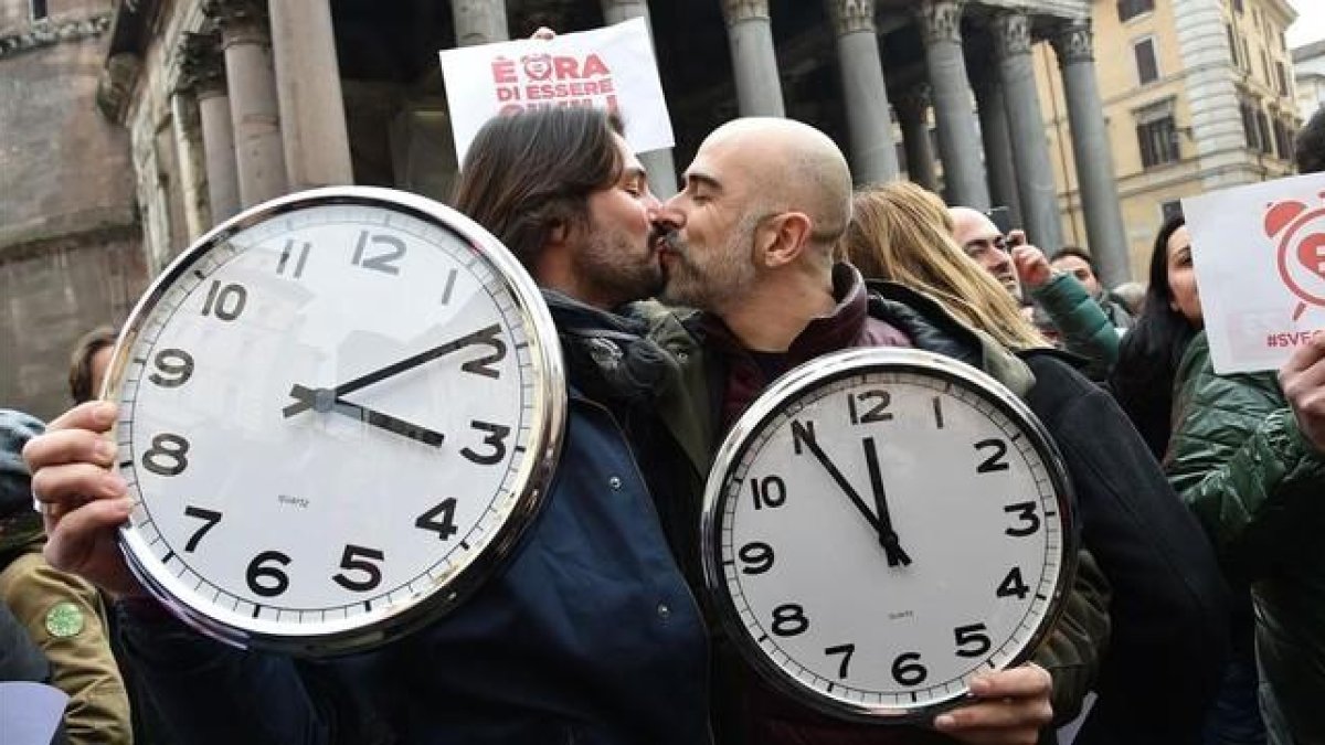 Una pareja con dos grandes relojes en la manifestación de Roma.