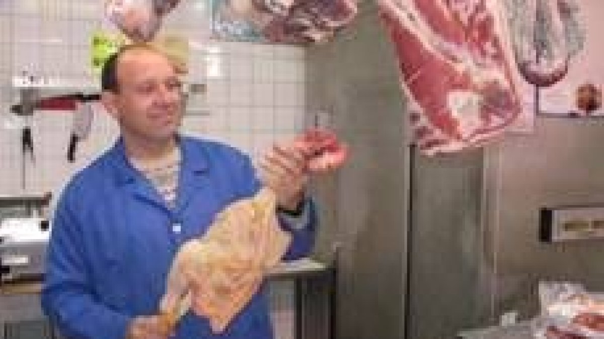 Un comerciante de la plaza de abastos muestra a la clientela un ejemplar de pollo de corral