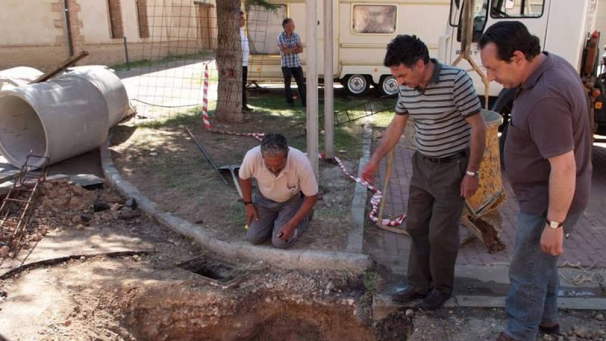 El alcalde (en medio), durnate las labores para cubrir el agujero que se produjo en la calzada.