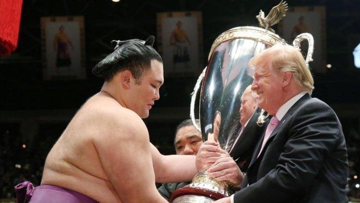 Trump recibe una copa de parte de un luchador de sumo, este domingo en Tokio.