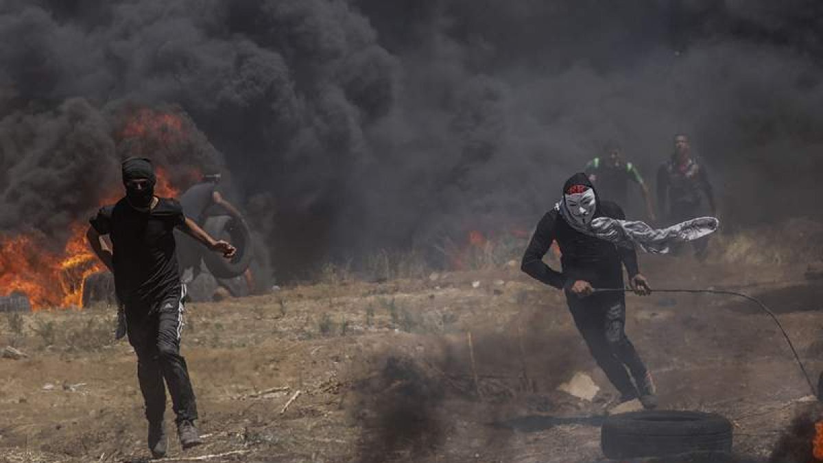 Dos palestinos durante los enfrentamientos en el este de la franja de Gaza. MOHAMMED SABER