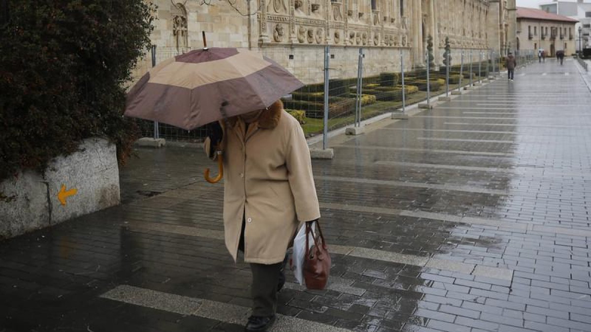 Una mujer sujeta su paraguas al pasar por San Marcos
