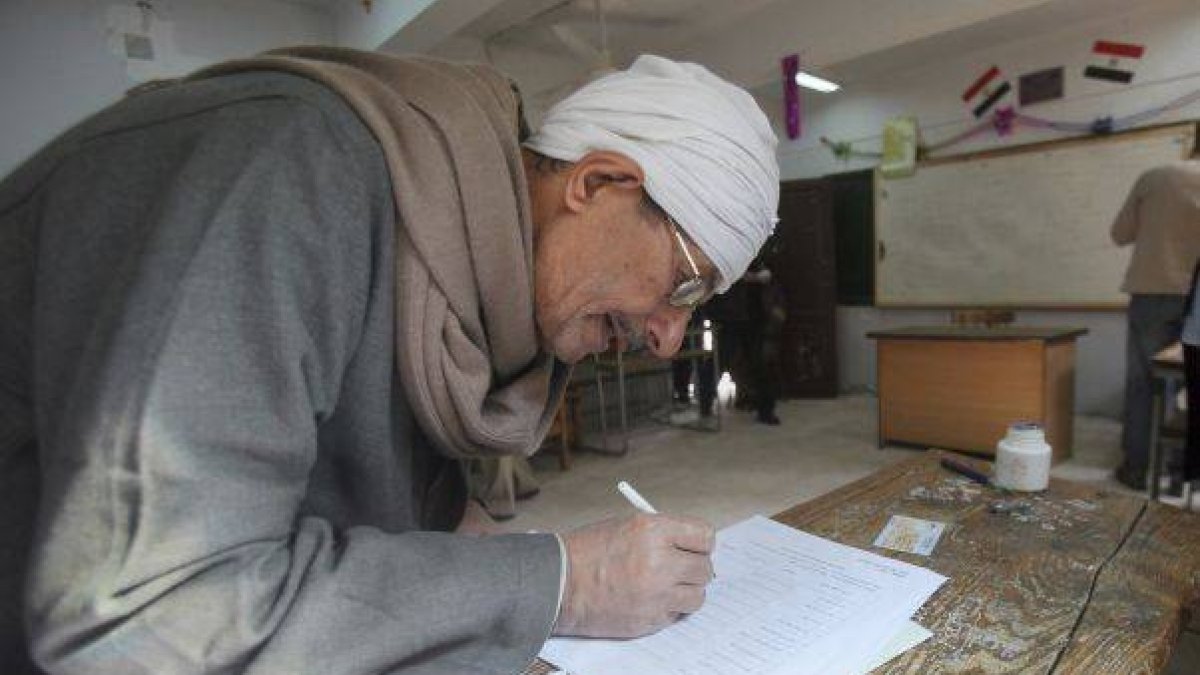 Un egipcio cumplimenta su papeleta antes de votar en la primera ronda de las elecciones legislativas, en un colegio electoral en El Cairo.