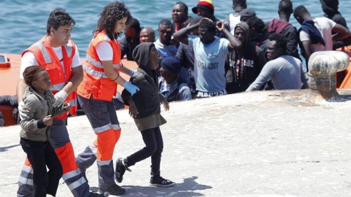 Dos menores acompañados por miembros de la Cruz Roja, a su llegada al puerto de Tarifa (Cádiz).
