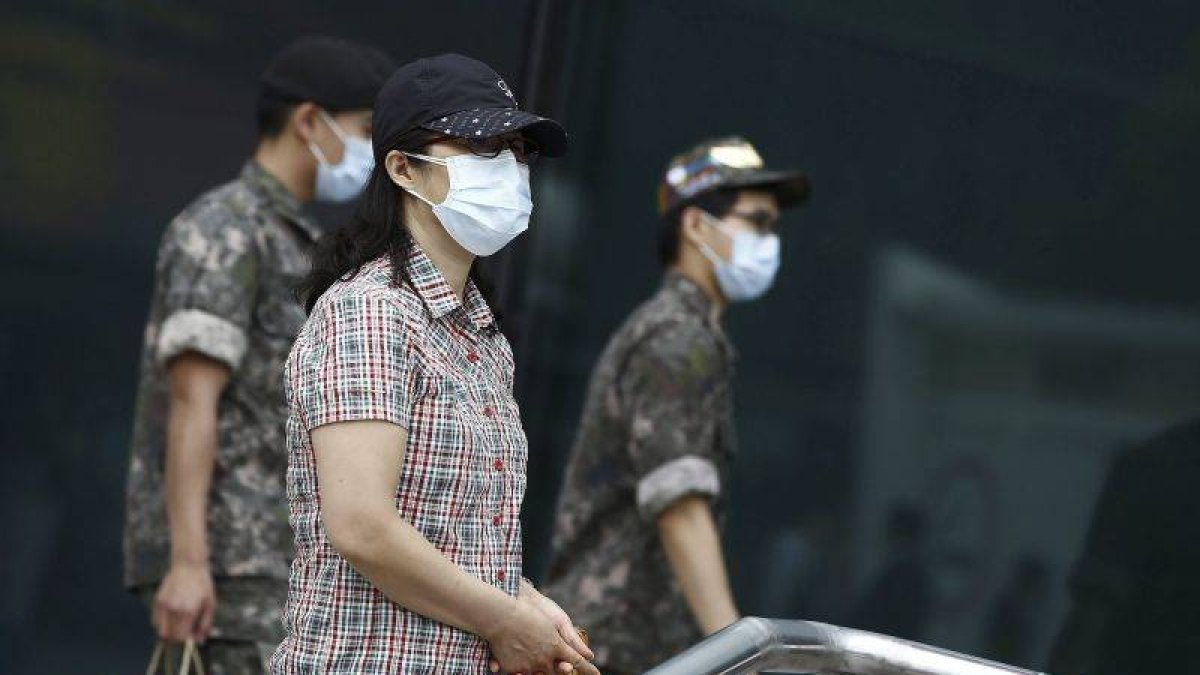 Soldados y civiles pasean con mascarillas por las calles de Seúl.