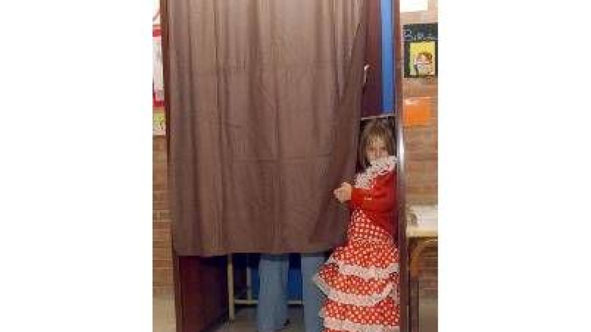 Una niña vestida de sevillana observa en un colegio electoral murciano