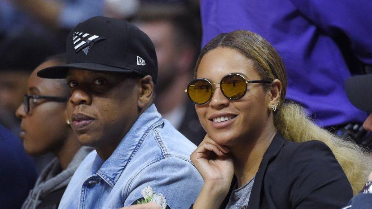 El rapero Jay Z (izq) y su esposa, la cantante Beyonce, asisten a un partido de la NBA.
