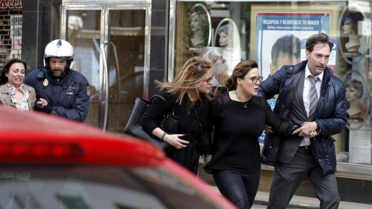Agentes de la Policía Nacional liberan a uno de los cinco rehenes retenidos hoy, durante poco más de media hora, en el interior de una sucursal de Caixabank, situada en la avenida de la Constitución de Gijón.