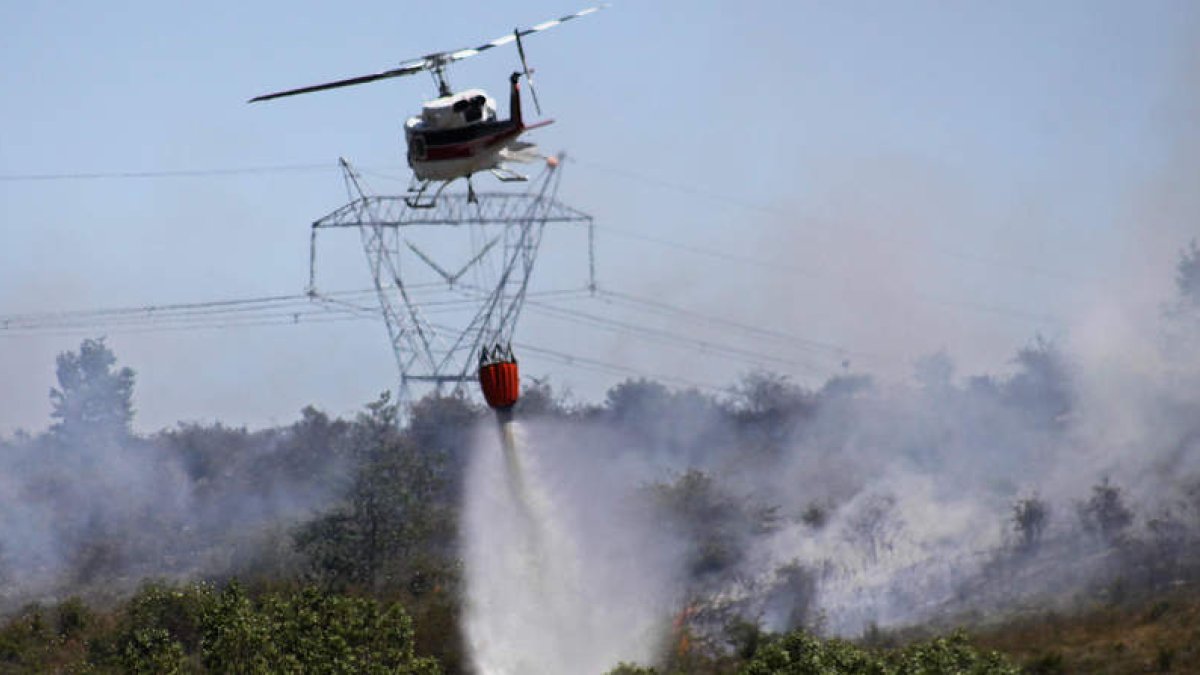 El helicóptero descarga agua en la zona en la que se produjo la quema de rastrojos