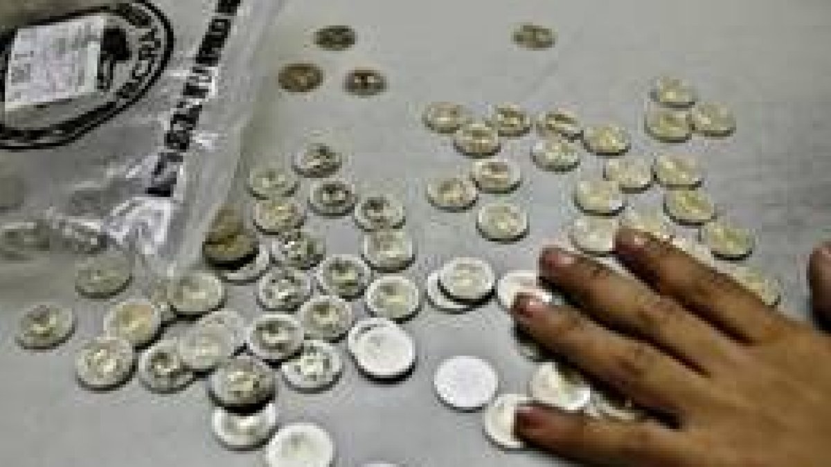 Una empleada cuenta monedas en un puesto de la estación de trenes de Retiro, en Buenos Aires