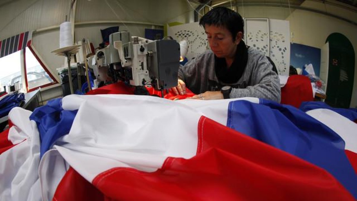 Una trabajadora de la empresa Doublet cose una bandera francesa, ayer en Lille.