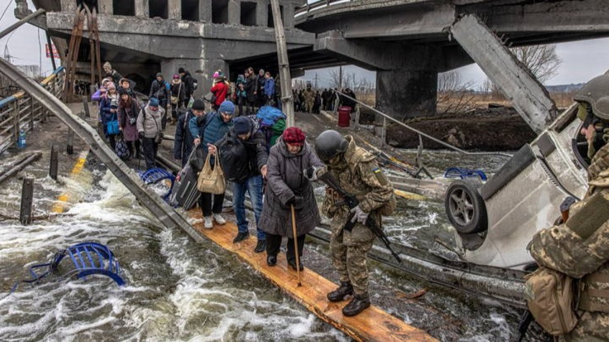 Civiles ucranianos cruzan un puente destruido mientras huyen del asedio en la ciudad de Irpin. ROMAN PILIPEY
