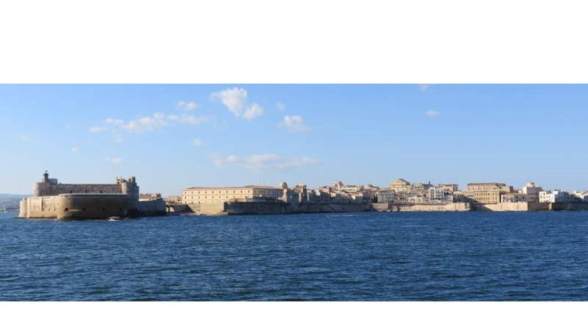 Desde el mar se dibuja el perfil de la isla, con el castillo Maniace a la izquierda.