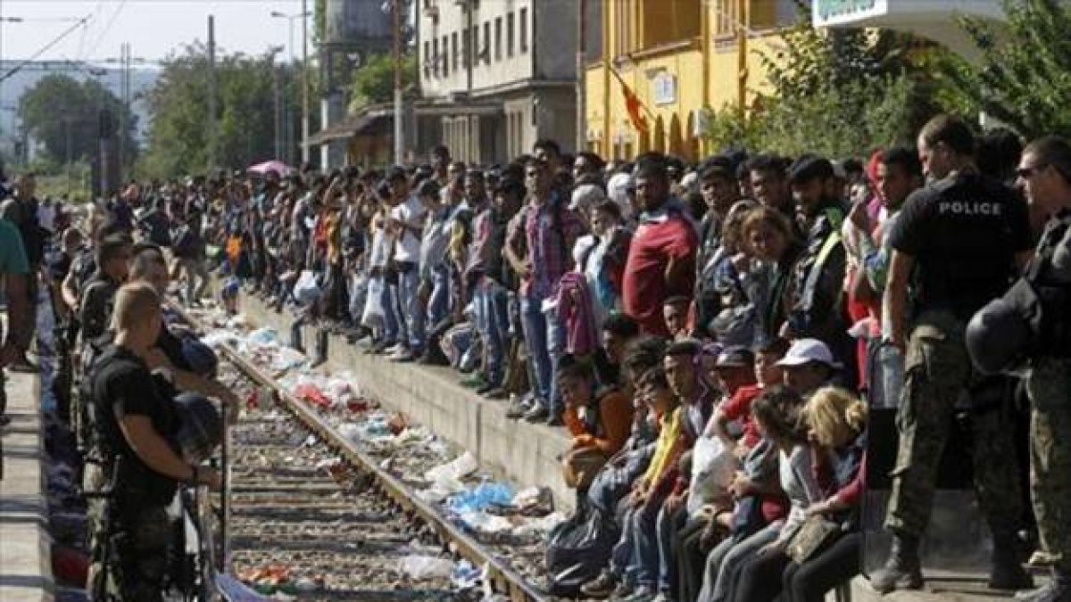 Miles de refugiados esperan un tren que les permita cruzar Macedonia y llegar a Serbia para luego pasar la frontera con Hungría, donde se erige una prolongada valla.