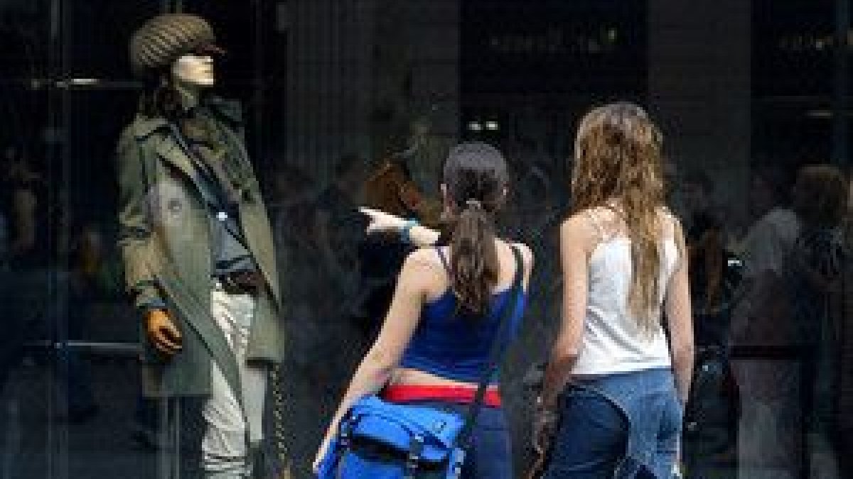 Unas mujeres miran un escaparate de una tienda de ropa femenina, en Barcelona.