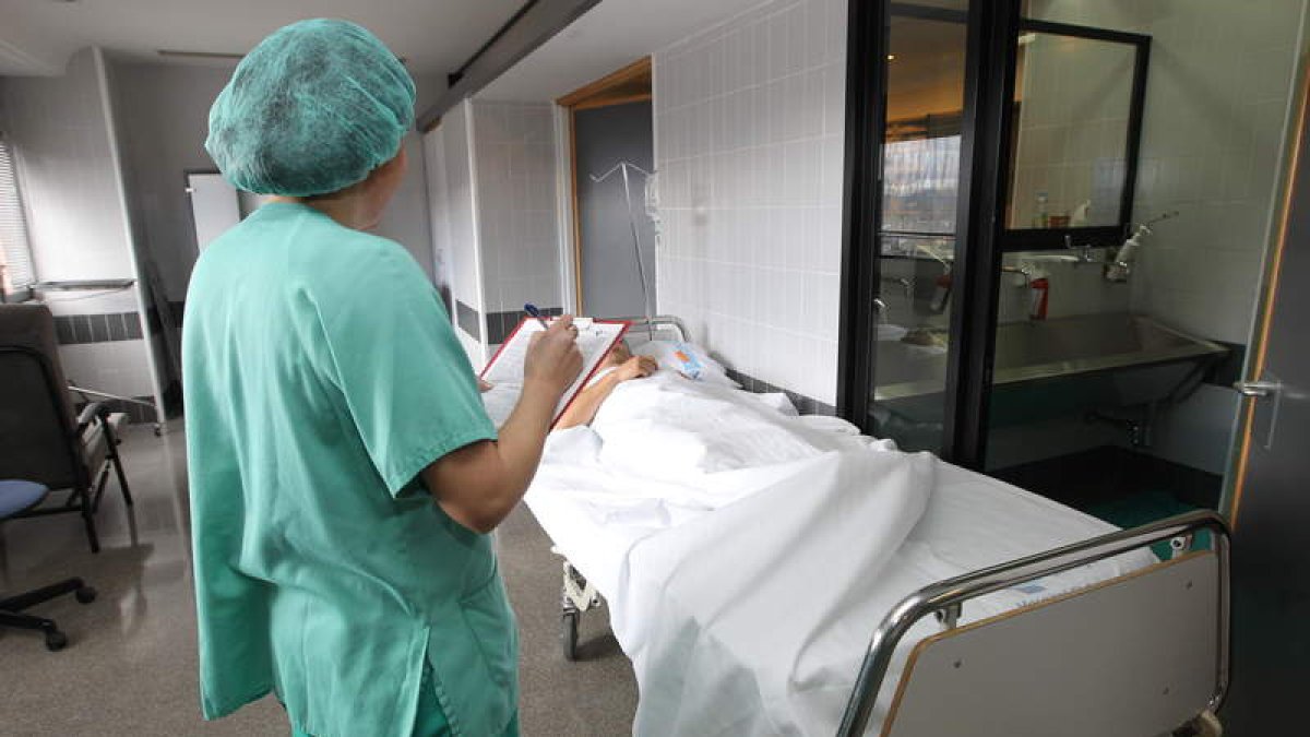 Una trabajadora del Hospital del Bierzo controla a uno de los pacientes ingresados en el centro asistencial, en una imagen de archivo.
