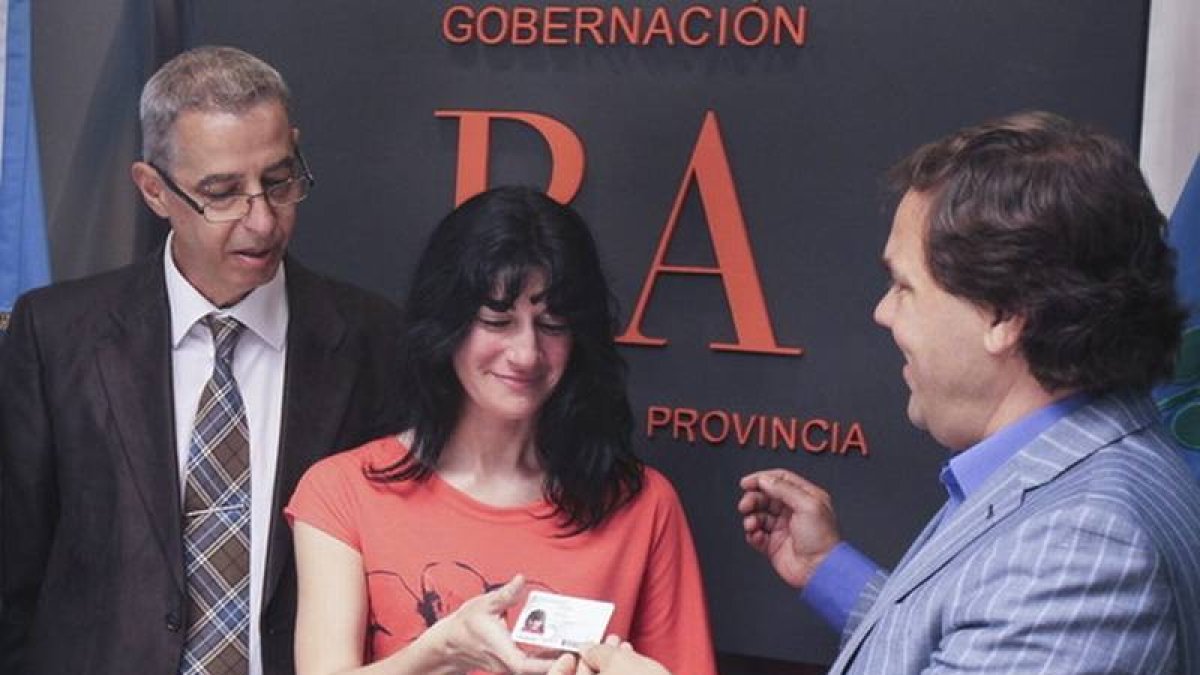 La madre de Luana, Gabriela, recibe el documento de identidad de su hija de manos del jefe de Gabinete del Gobierno provincial de Buenos Aires, Alberto Pérez (derecha), ante el presidente de la comunidad homosexual de Argentina, César Cigliutti.