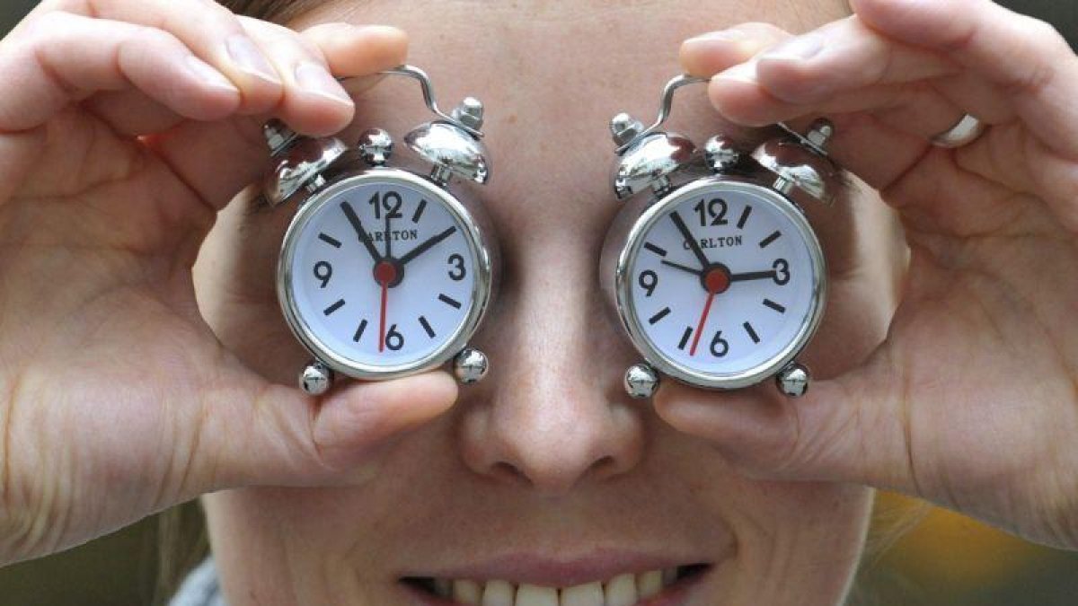 Una mujer muestra dos relojes con el cambio de hora, en una foto de archivo.