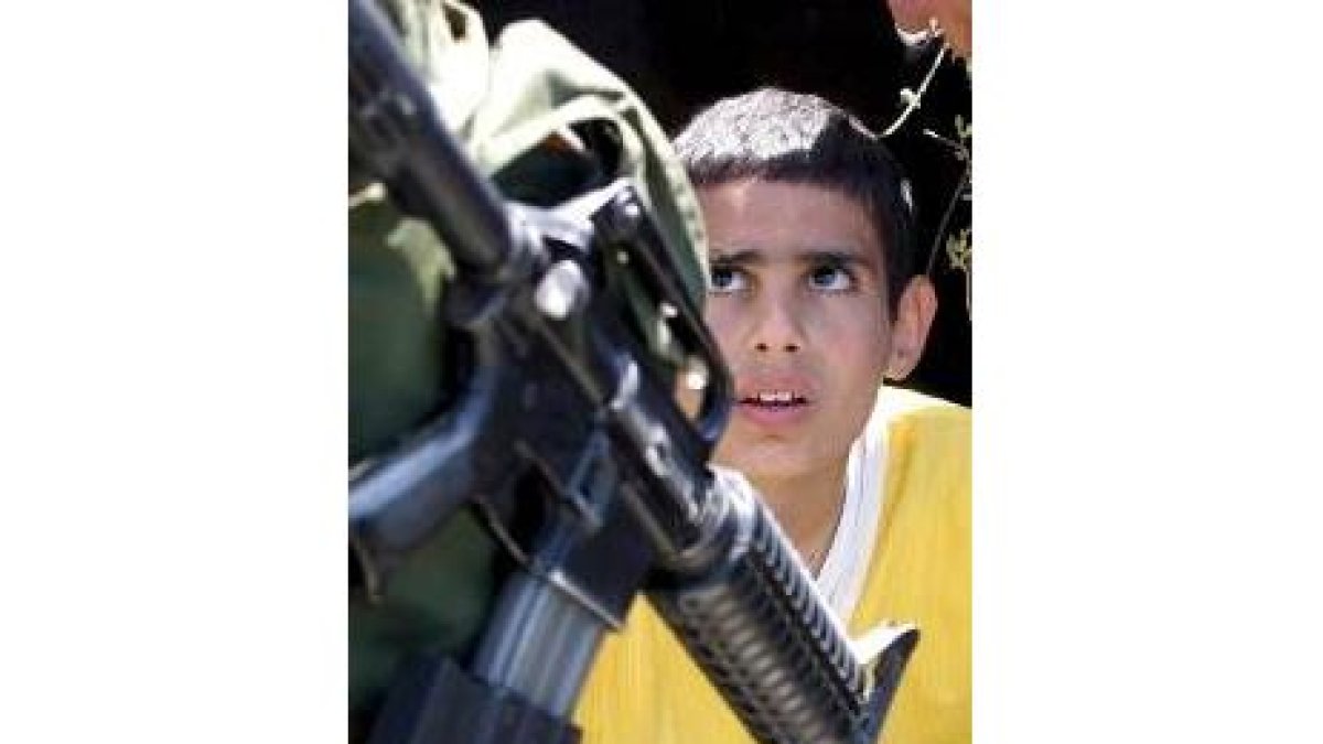 Un niño palestino observa a un soldado israelí en el pueblo de Nileen