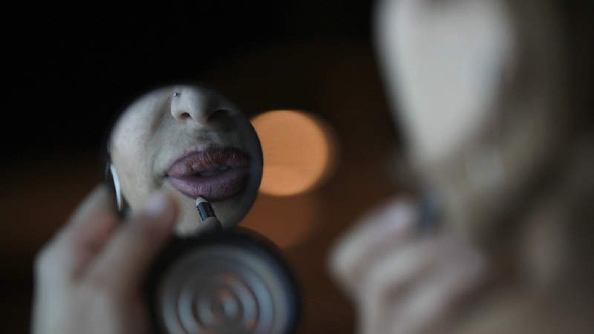 Una mujer se pinta los labios mientras espera en la calle donde ejerce la prostitución. JESÚS F. SALVADORES