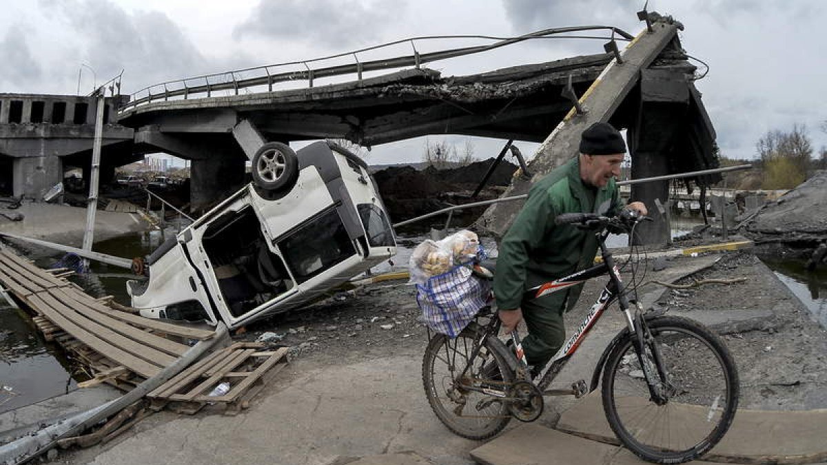 Un hombre con una bicicleta
cruza el puente destruido a
las fueras de la ciudad
reconquistada de Irpin. ANDRII
NESTERENKO