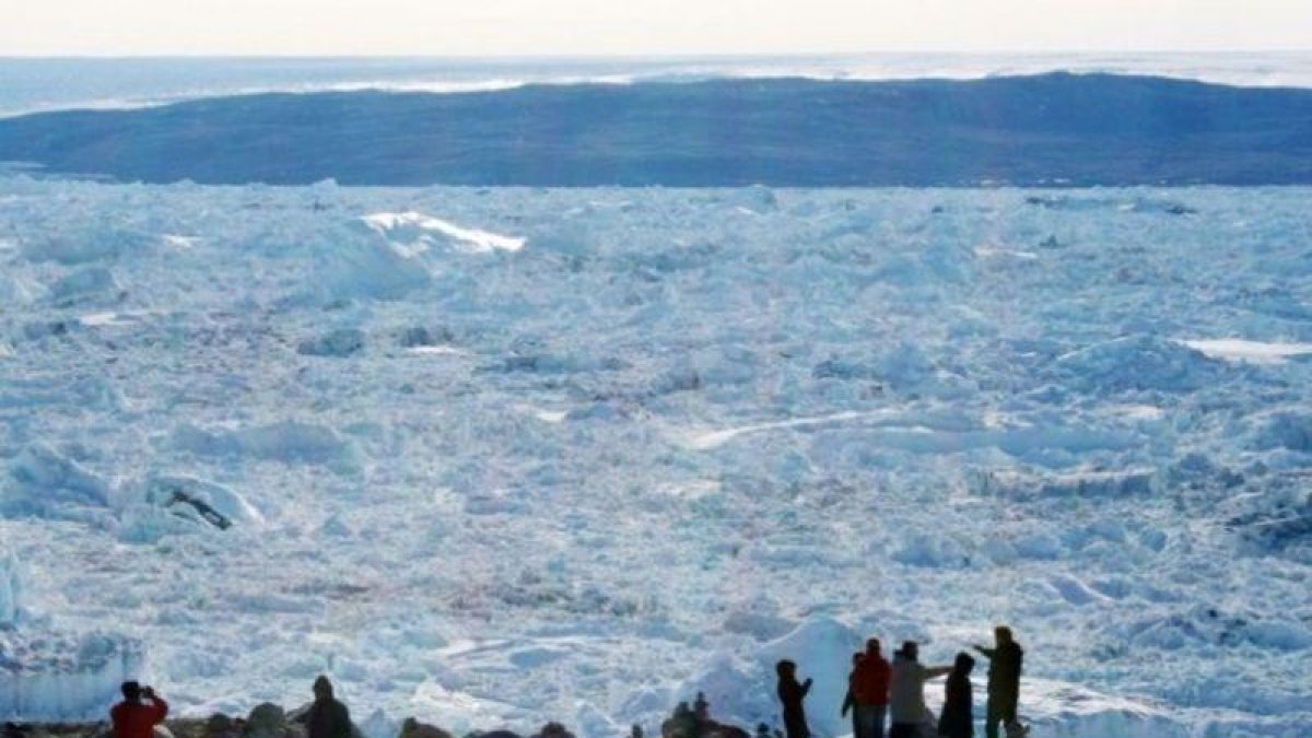Un grupo de turistas contempla el hielo del fiordo de Ilulissat  en la costa oeste de Groenlandia. El deshielo se multiplica por cuatro en 10 años.
