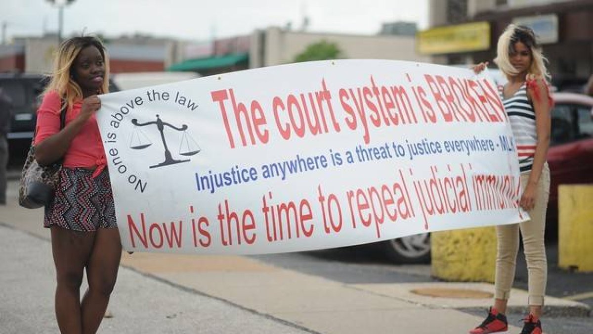 Dos jóvenes protestan en Ferguson con una pancarta contra el sistema judicial estadounidense.
