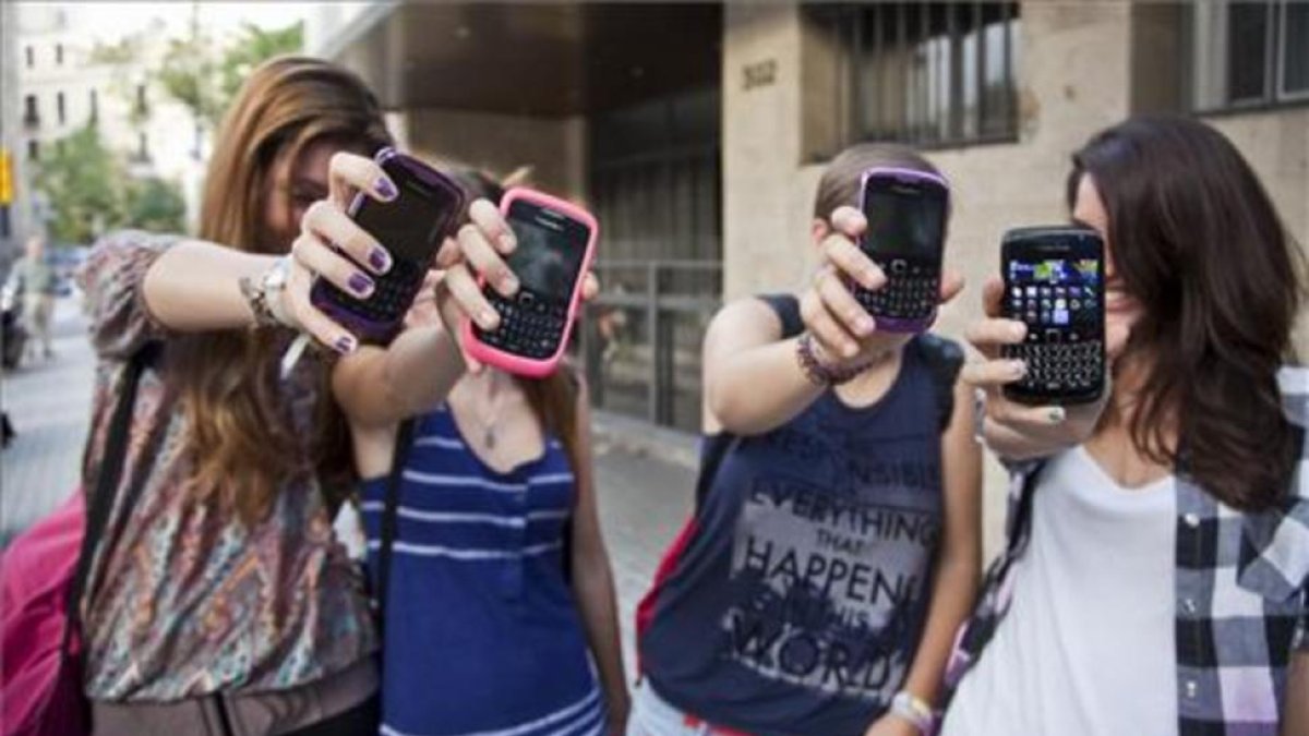 Unas adolescentes muestran sus teléfonos móviles a la puerta de su instituto en Barcelona.