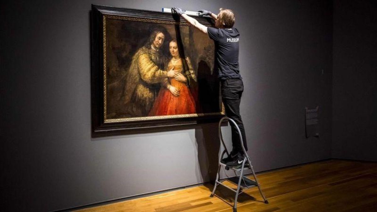 Unos operarios del Rijksmuseum cuelgan La novia judía, de Rembrandt, para la exposición que el museo dedica al artista en el 350 aniversario de su muerte.