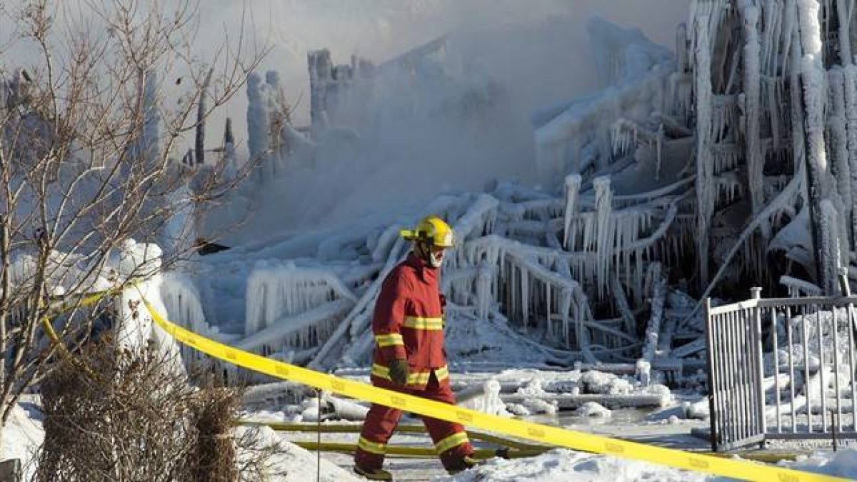 Un bombero camina entre los restos de la residencia incendiada en L'Isle-Verte (Canadá), este jueves.